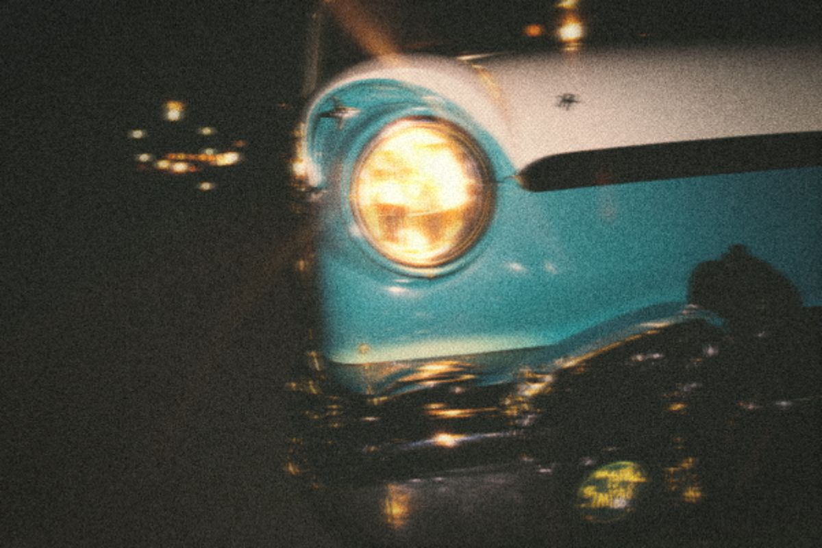 Chrome bumper and round headlight of a classic car at night
