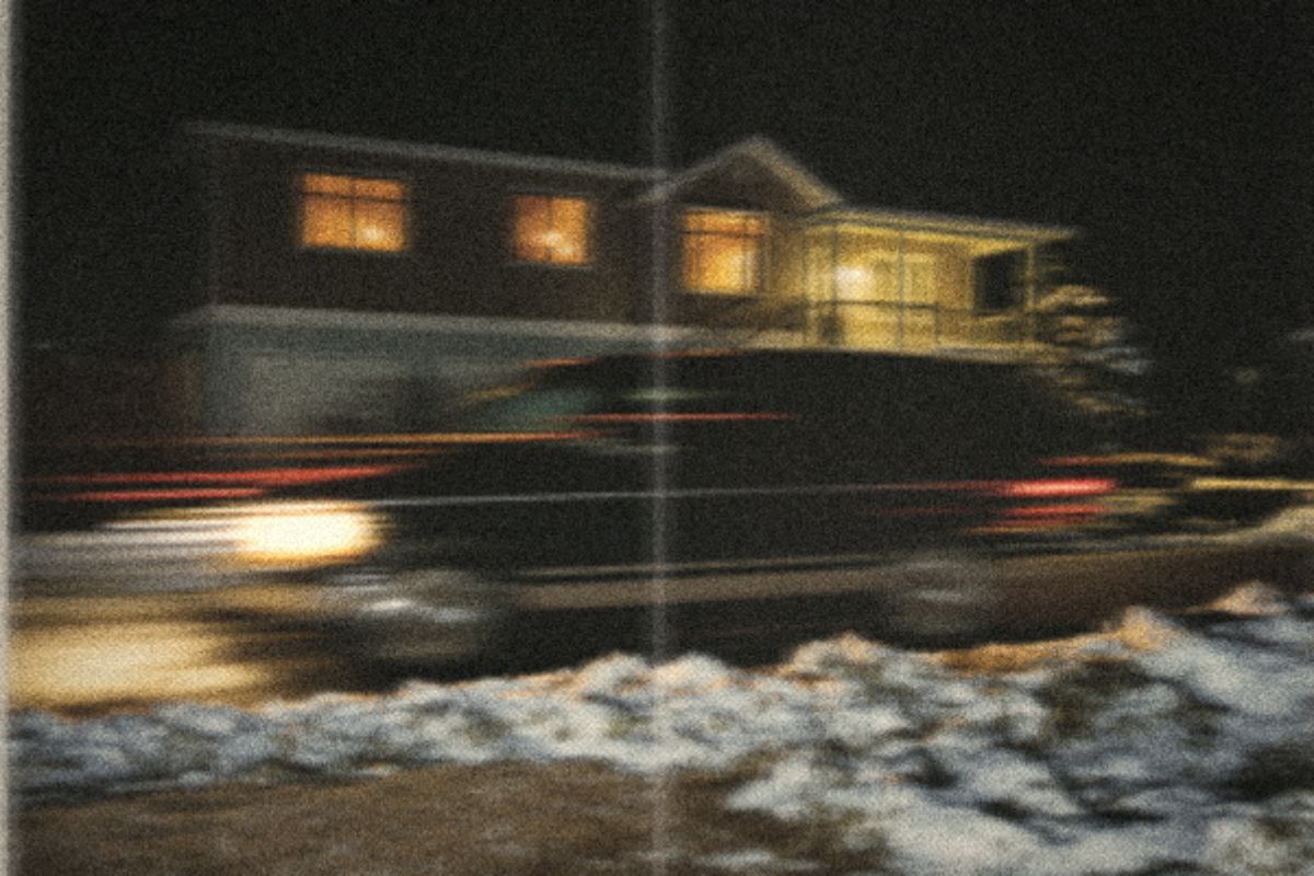 Family SUV pulling up to a house with warm lights on a winter evening