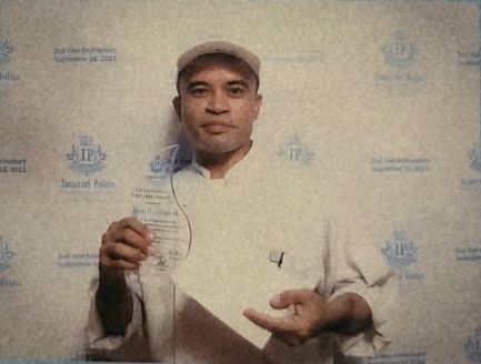 Junior in chef whites holding an award at a hotel anniversary event