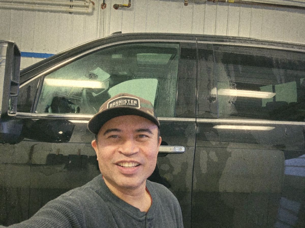 Junior smiling in the wash bay in front of a freshly washed black truck